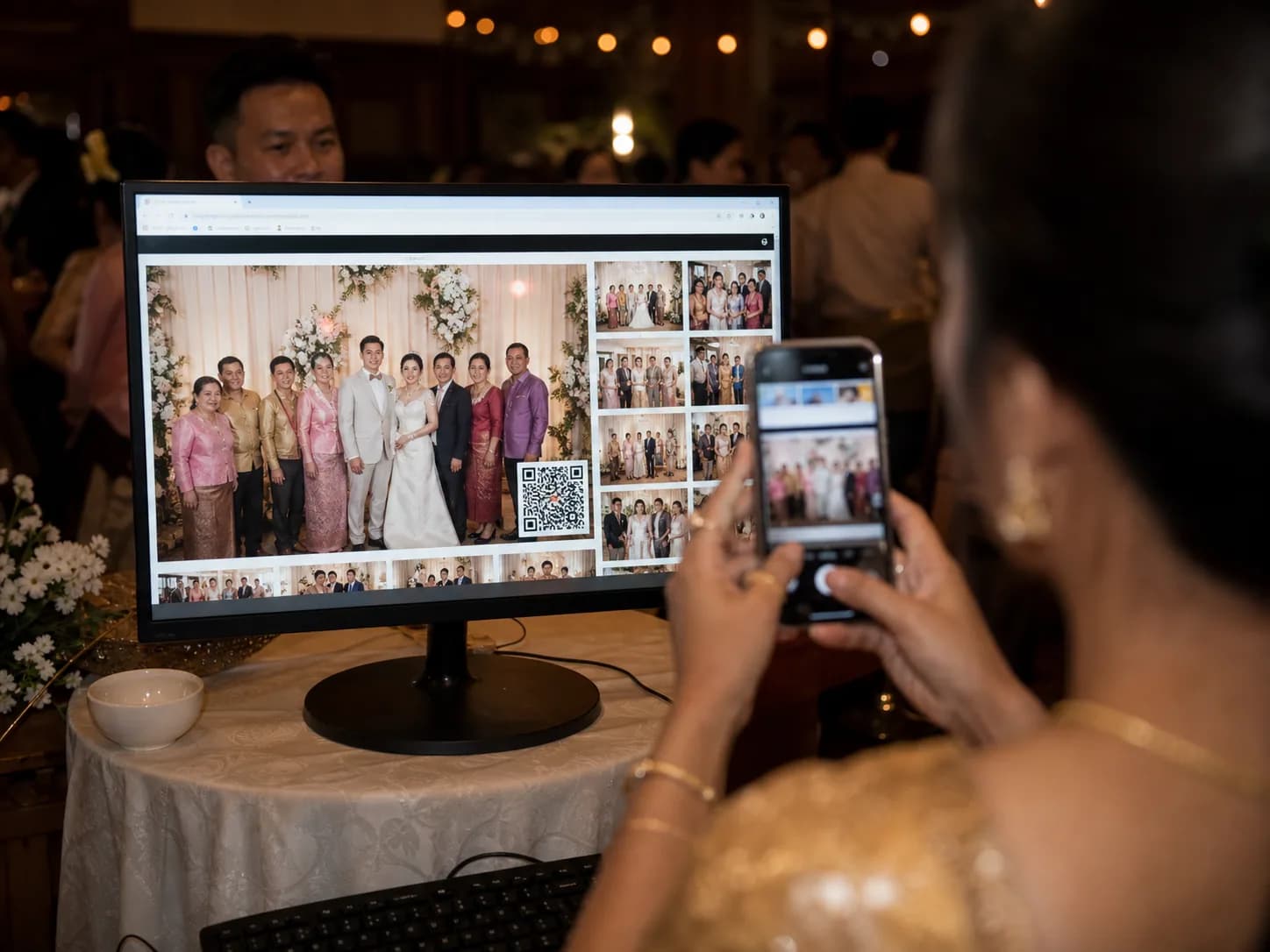 A wedding guest photographing a live gallery on a screen with her phone