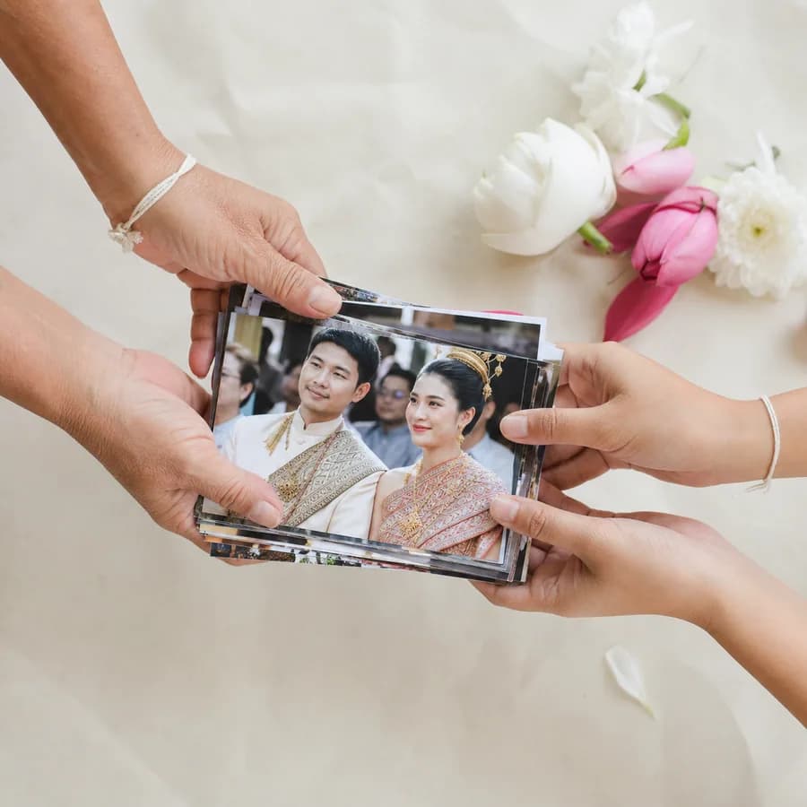 A stack of printed event photos being handed from one person to another